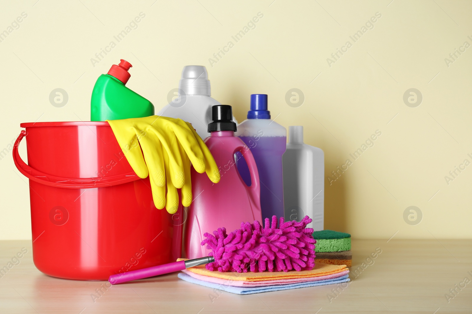 Photo of Different cleaning supplies and tools on table against beige. Space for text