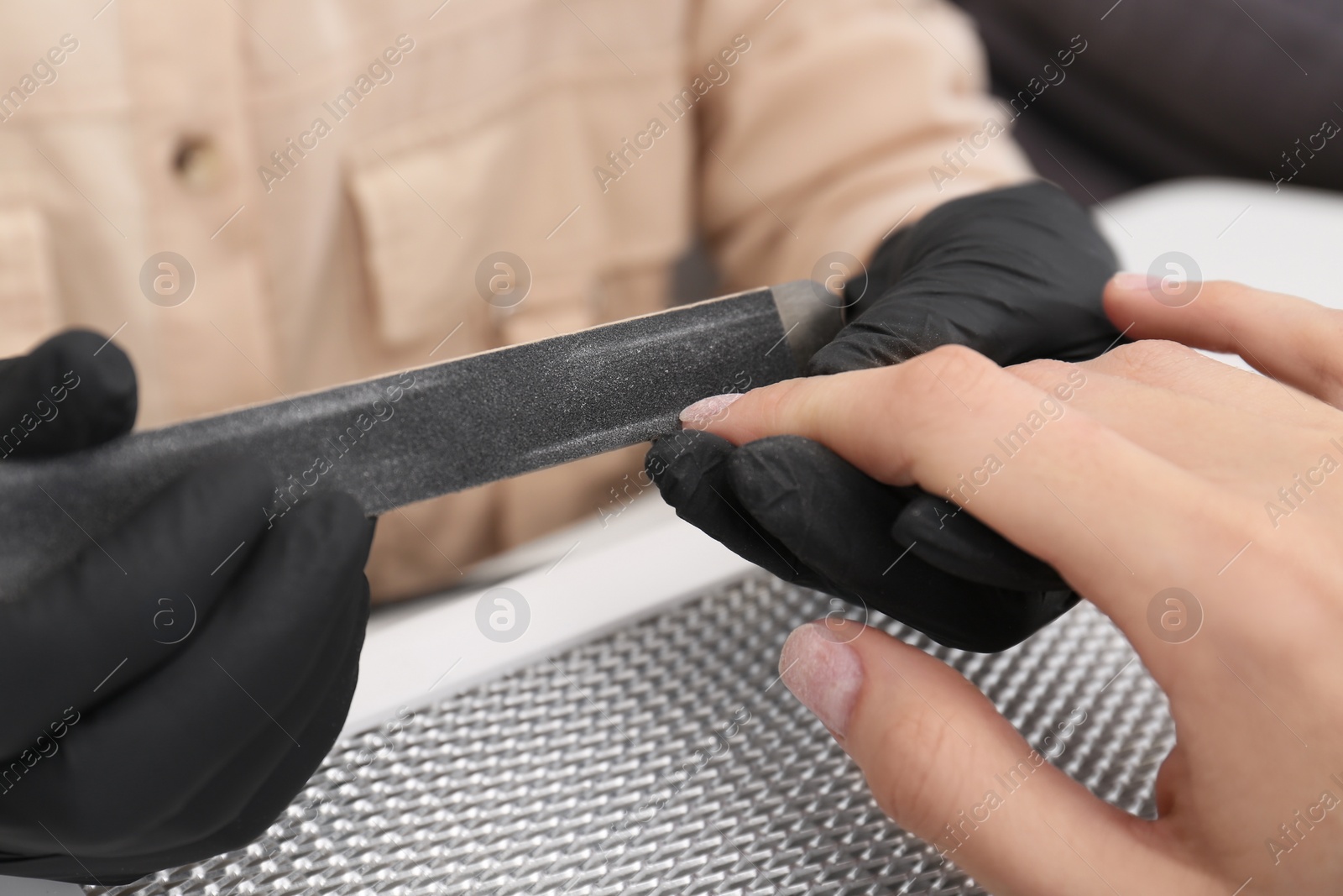 Photo of Professional manicurist working with client, closeup view