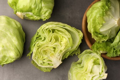 Photo of Fresh green cut and whole iceberg lettuce heads on grey table, flat lay