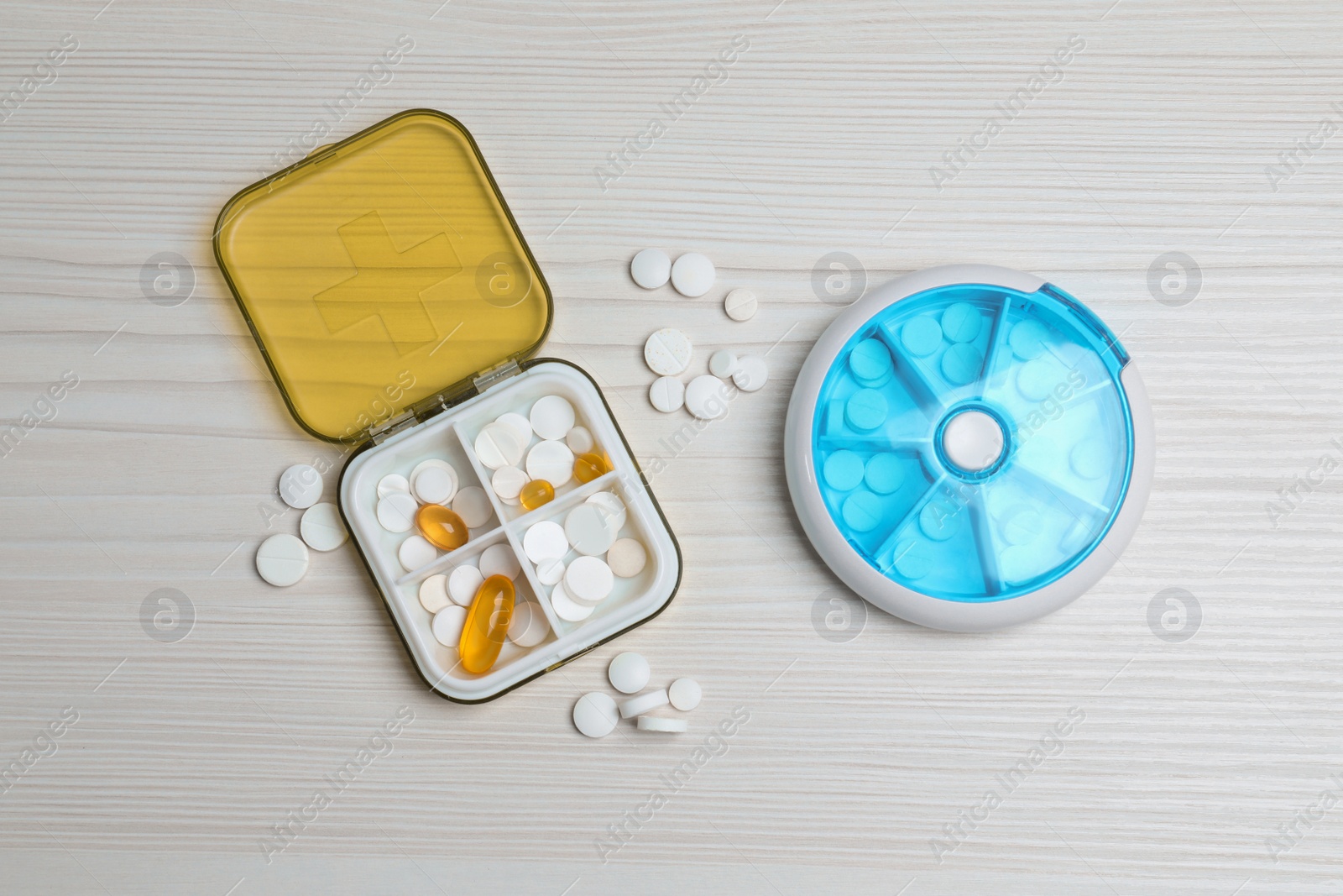 Photo of Pill boxes with medicaments on white wooden table, flat lay