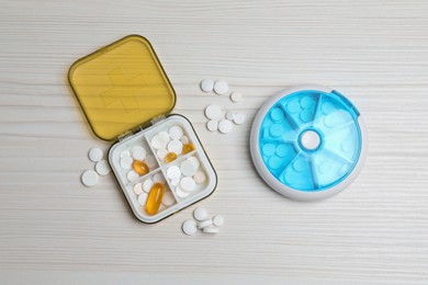 Photo of Pill boxes with medicaments on white wooden table, flat lay