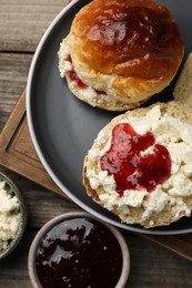 Photo of Freshly baked soda water scones with cranberry jam and butter on wooden table, flat lay