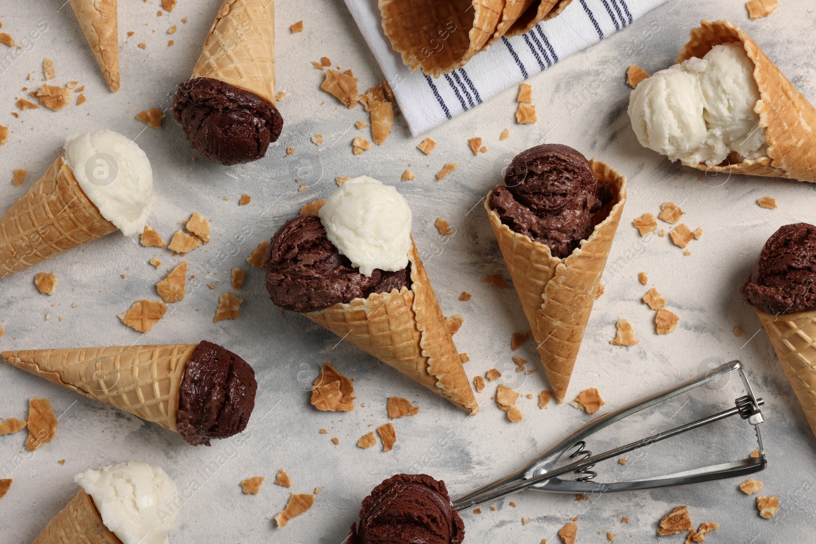 Photo of Flat lay composition with tasty ice cream scoops in waffle cones on light textured table