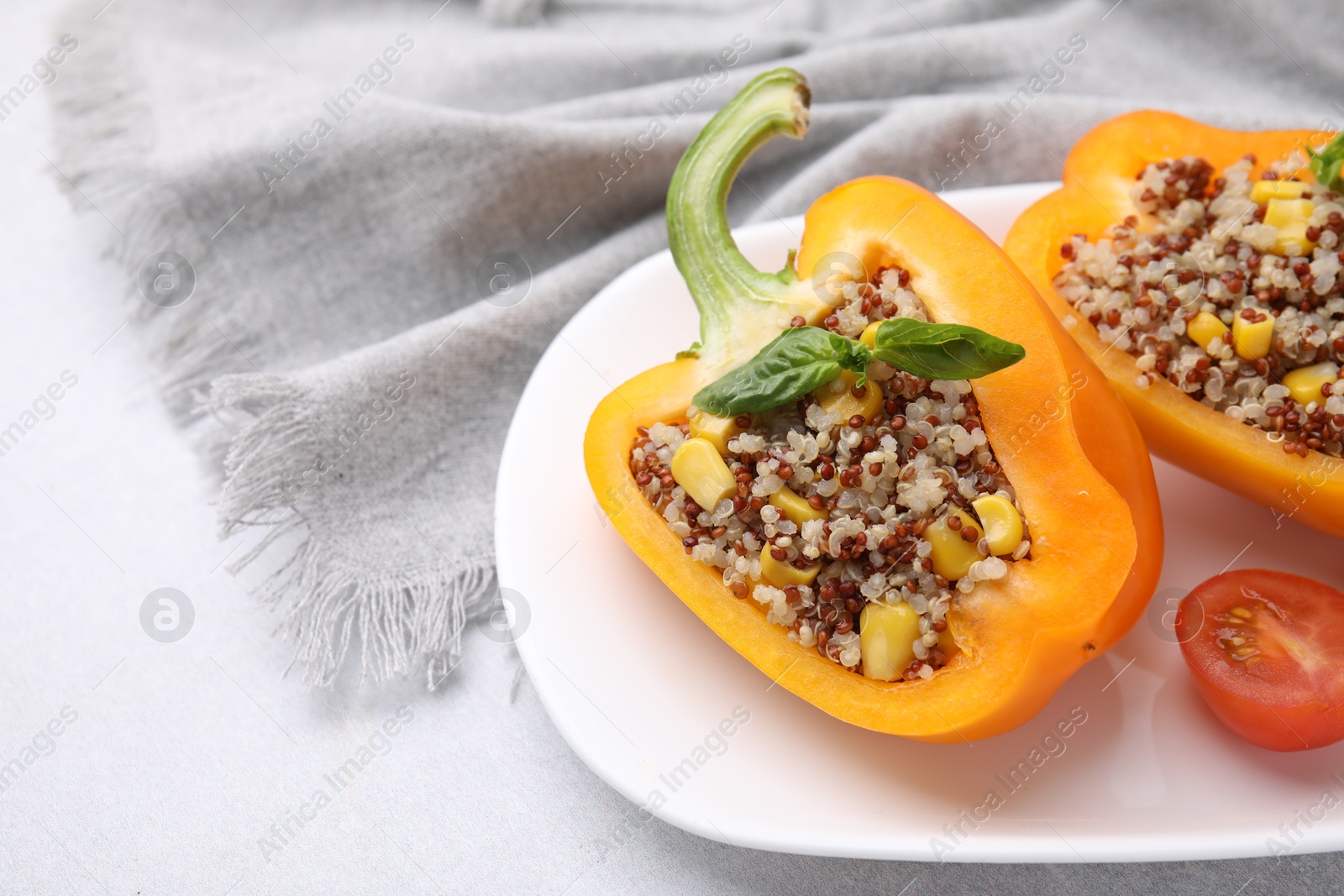 Photo of Quinoa stuffed bell pepper with basil and tomato on light table, closeup. Space for text