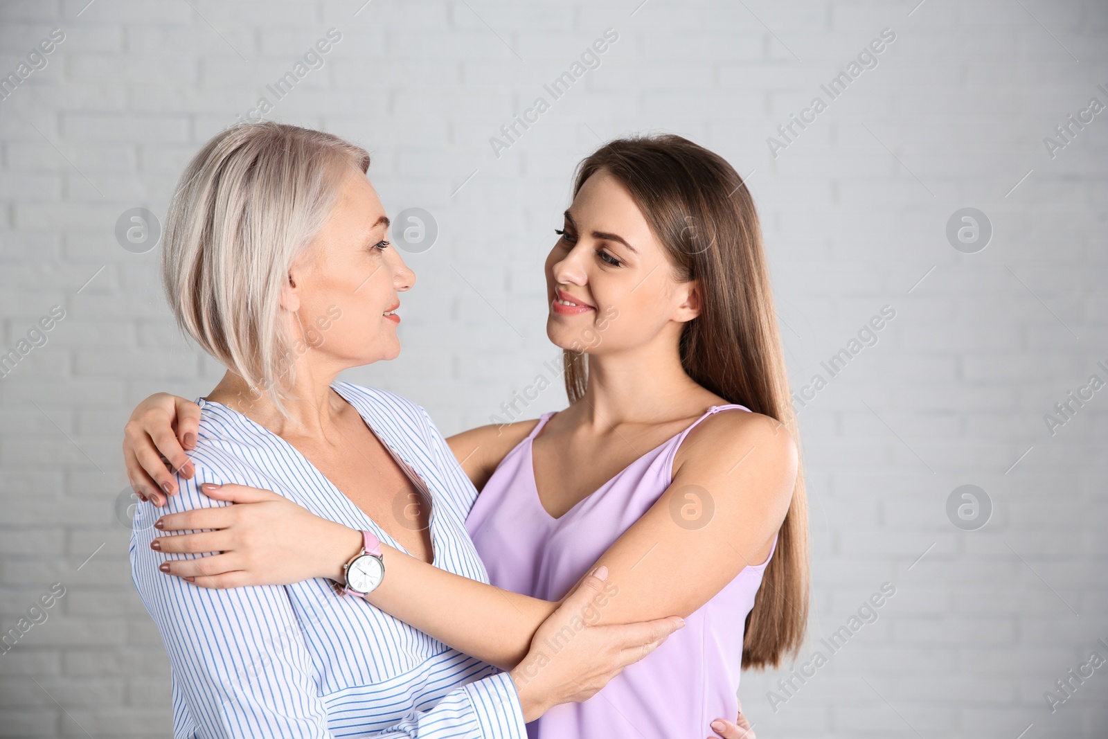 Photo of Portrait of young woman with her mature mother near brick wall