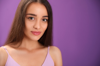 Portrait of beautiful young woman on purple background. Space for text