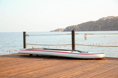 SUP board with paddle on wooden pier near sea