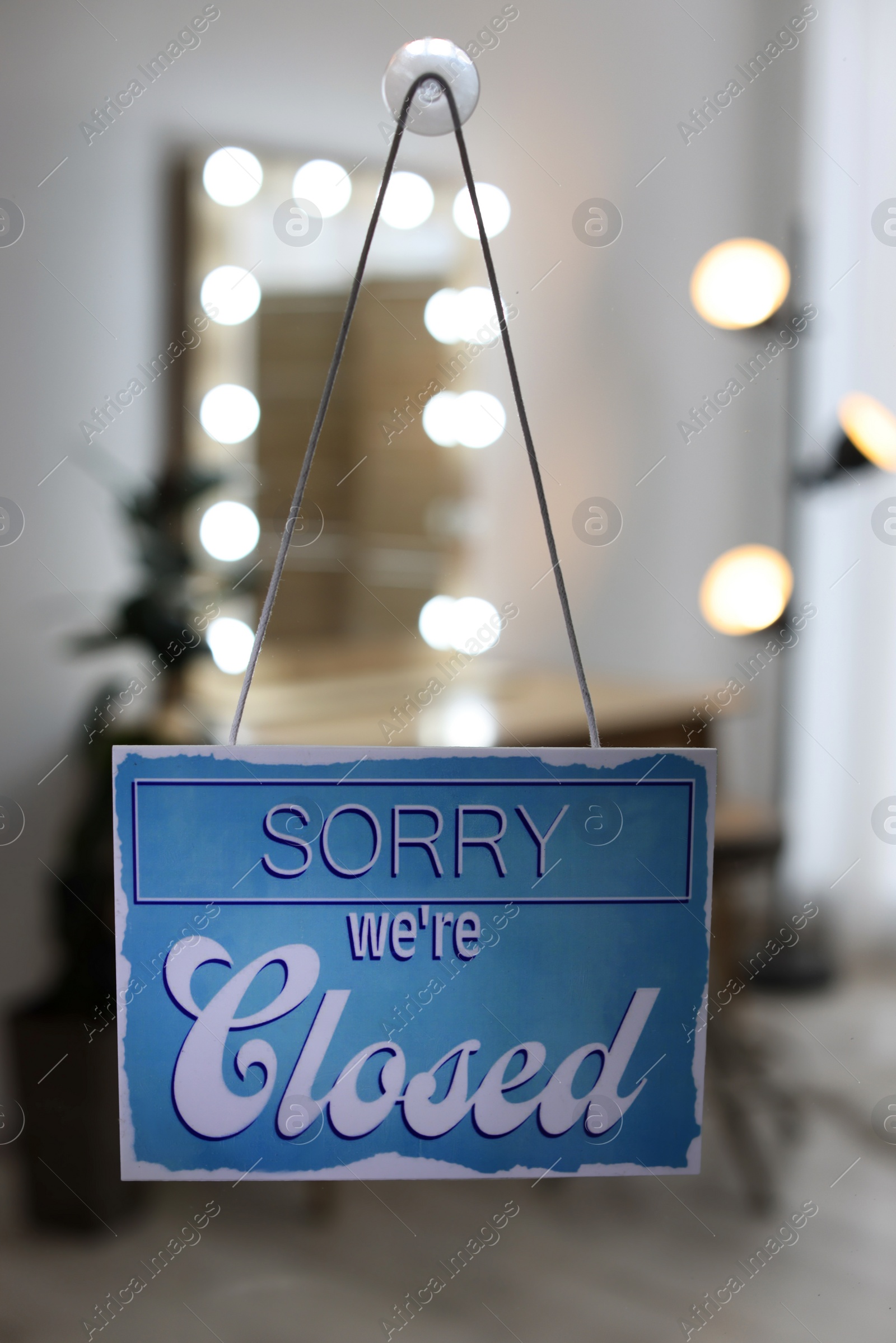 Photo of Light blue sign with text Sorry we're Closed hanging on glass door. Coronavirus quarantine