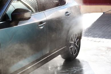 Cleaning automobile with high pressure water jet at car wash