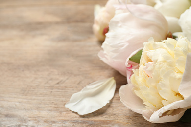 Photo of Beautiful peonies on wooden background, closeup. Space for text