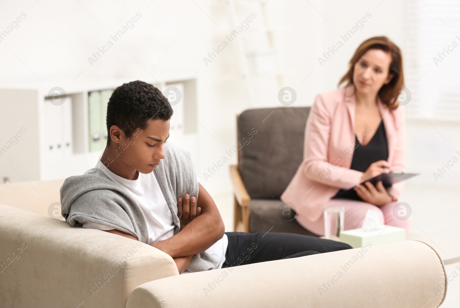 Photo of Psychotherapist working with teenage African-American boy in office