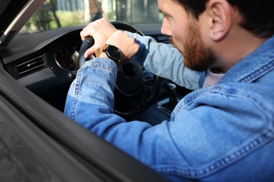 Man checking time on watch in car, closeup. Being late concept
