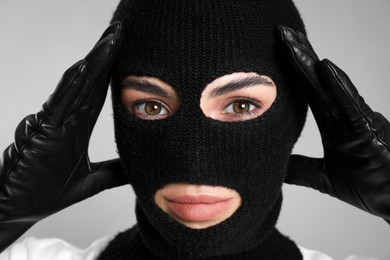 Photo of Woman wearing knitted balaclava on grey background, closeup