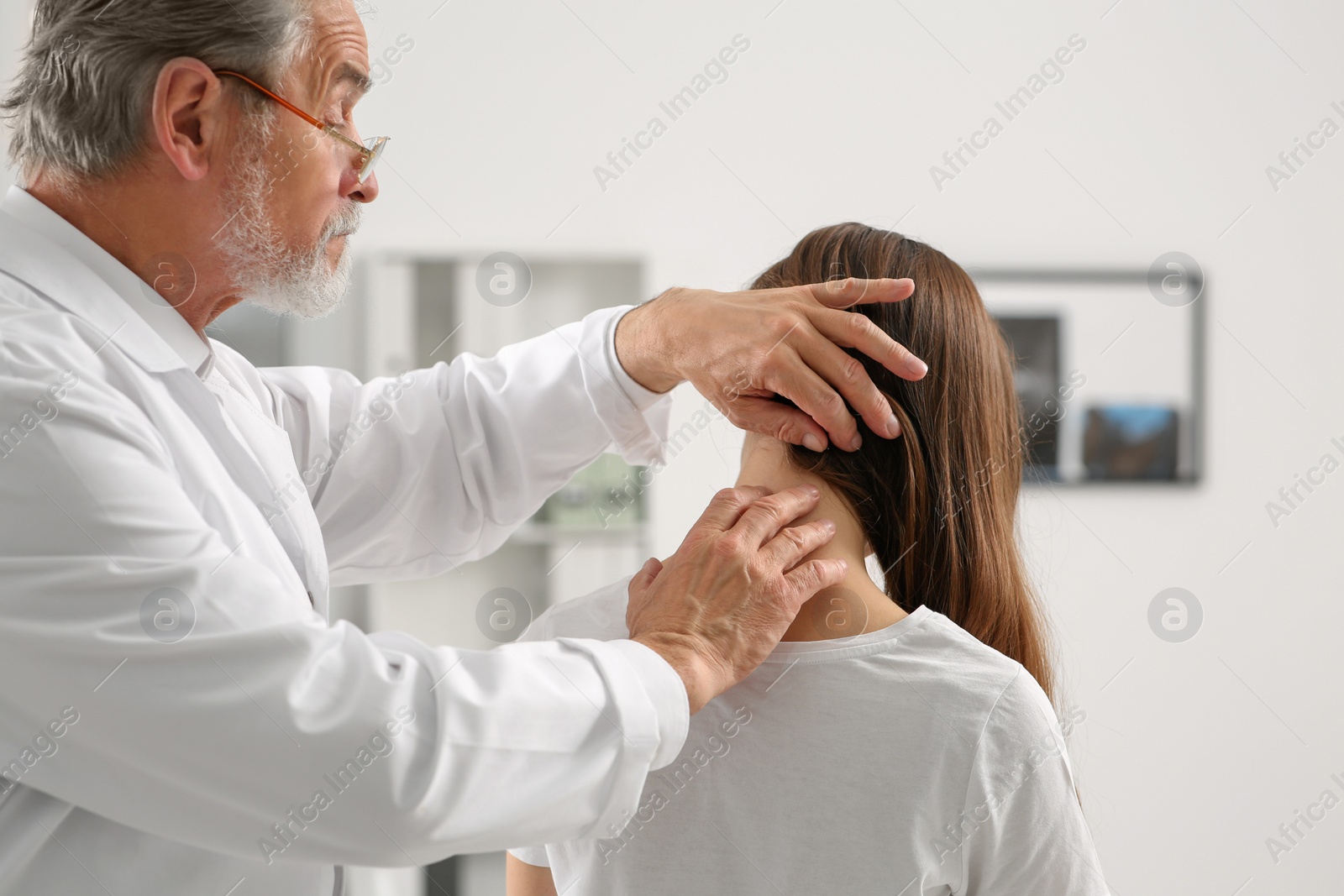 Photo of Professional orthopedist examining patient's neck in clinic