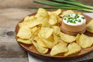 Photo of Chips with sour cream on wooden table, closeup