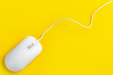 Photo of Modern wired optical mouse on yellow background, top view. Space for text