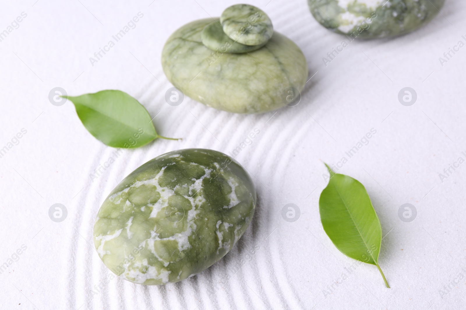 Photo of Zen garden stones and leaves on white sand with pattern