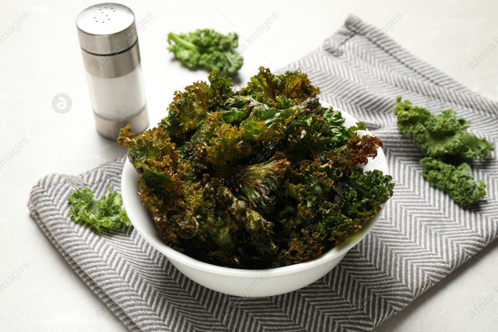 Photo of Tasty baked kale chips on grey marble table