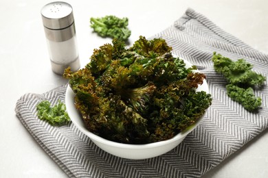 Photo of Tasty baked kale chips on grey marble table