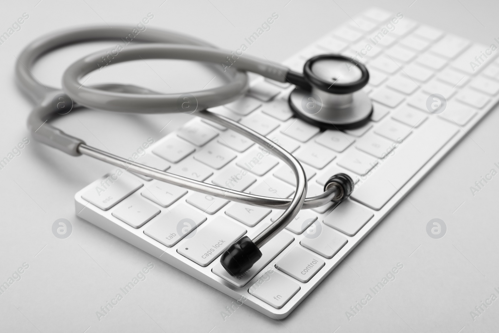 Photo of Keyboard and stethoscope on white background, closeup