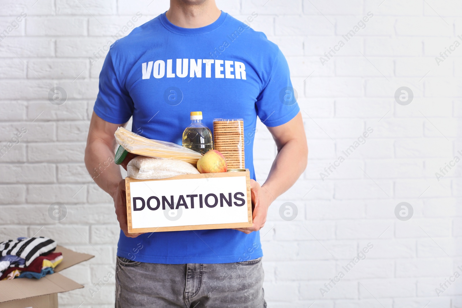 Photo of Male volunteer holding donation box with food products indoors