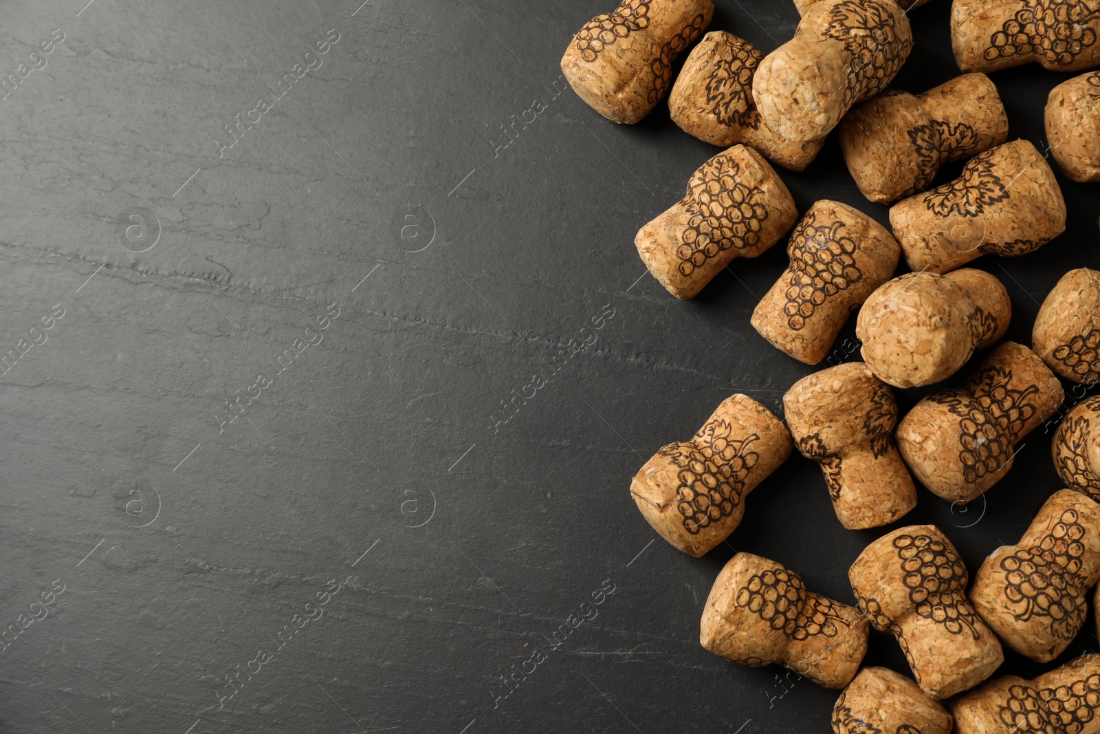 Photo of Sparkling wine corks with grape images on black table, flat lay. Space for text