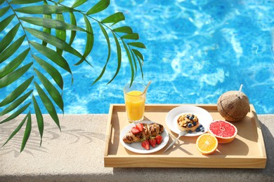 Image of View of beautiful green tropical leaves and tray with delicious breakfast near swimming pool