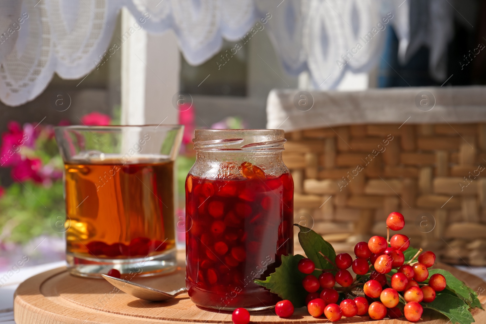 Photo of Tasty hot drink, jam and viburnum berries on wooden board indoors