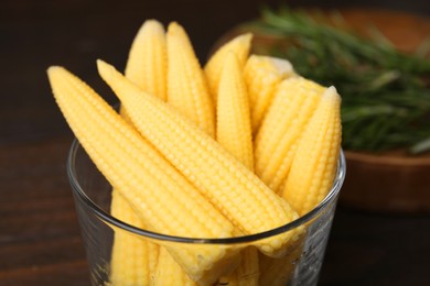 Tasty fresh yellow baby corns in glass on table, closeup