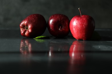 Photo of Wet red apples on dark grey table