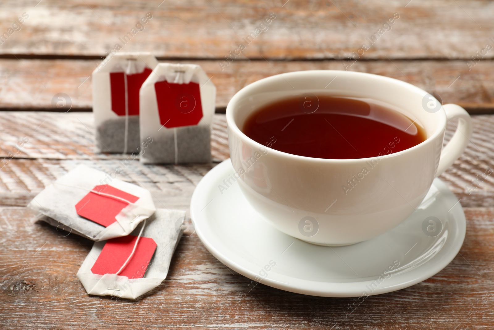 Photo of Tea bags and cup of aromatic drink on wooden rustic table