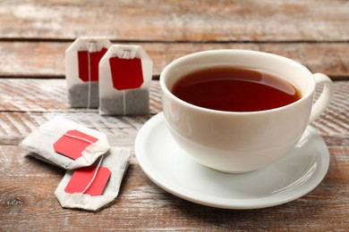 Tea bags and cup of aromatic drink on wooden rustic table