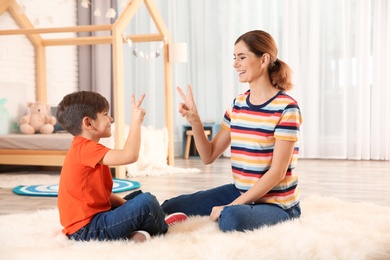 Hearing impaired mother and her child talking with help of sign language indoors