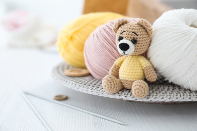 Crocheted bear and knitting supplies on white wooden table. Engaging in hobby