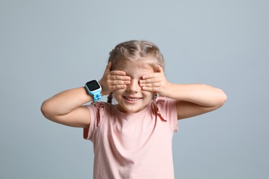 Photo of Little girl with smart watch on grey background