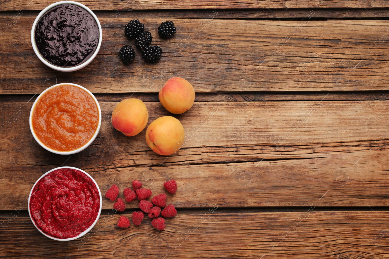 Photo of Different puree in bowls and fresh fruits on wooden table, flat lay. Space for text