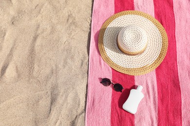 Photo of Beach towel with straw hat, sunglasses and sunscreen on sand, flat lay. Space for text