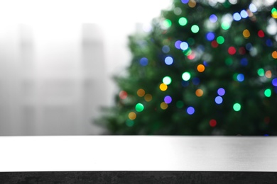 Photo of Empty table and blurred fir tree with colorful Christmas lights on background, bokeh effect. Space for design