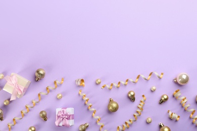 Beautiful serpentine streamers, Christmas balls and gift boxes on violet background, flat lay. Space for text