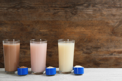 Protein shakes and powder on white wooden table