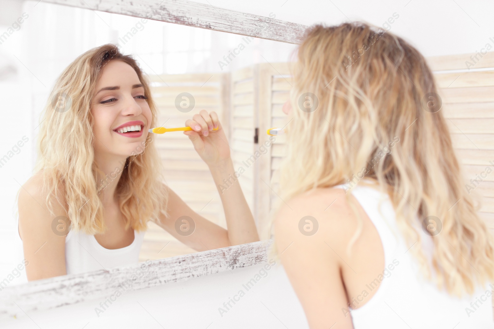 Photo of Young woman brushing her teeth in bathroom