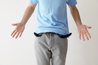 Photo of Man showing empty pockets on light background