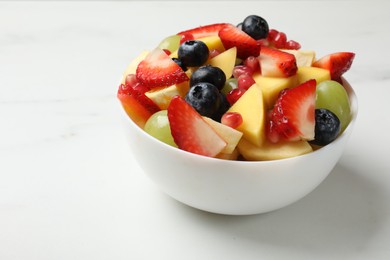 Photo of Tasty fruit salad in bowl on white table, closeup