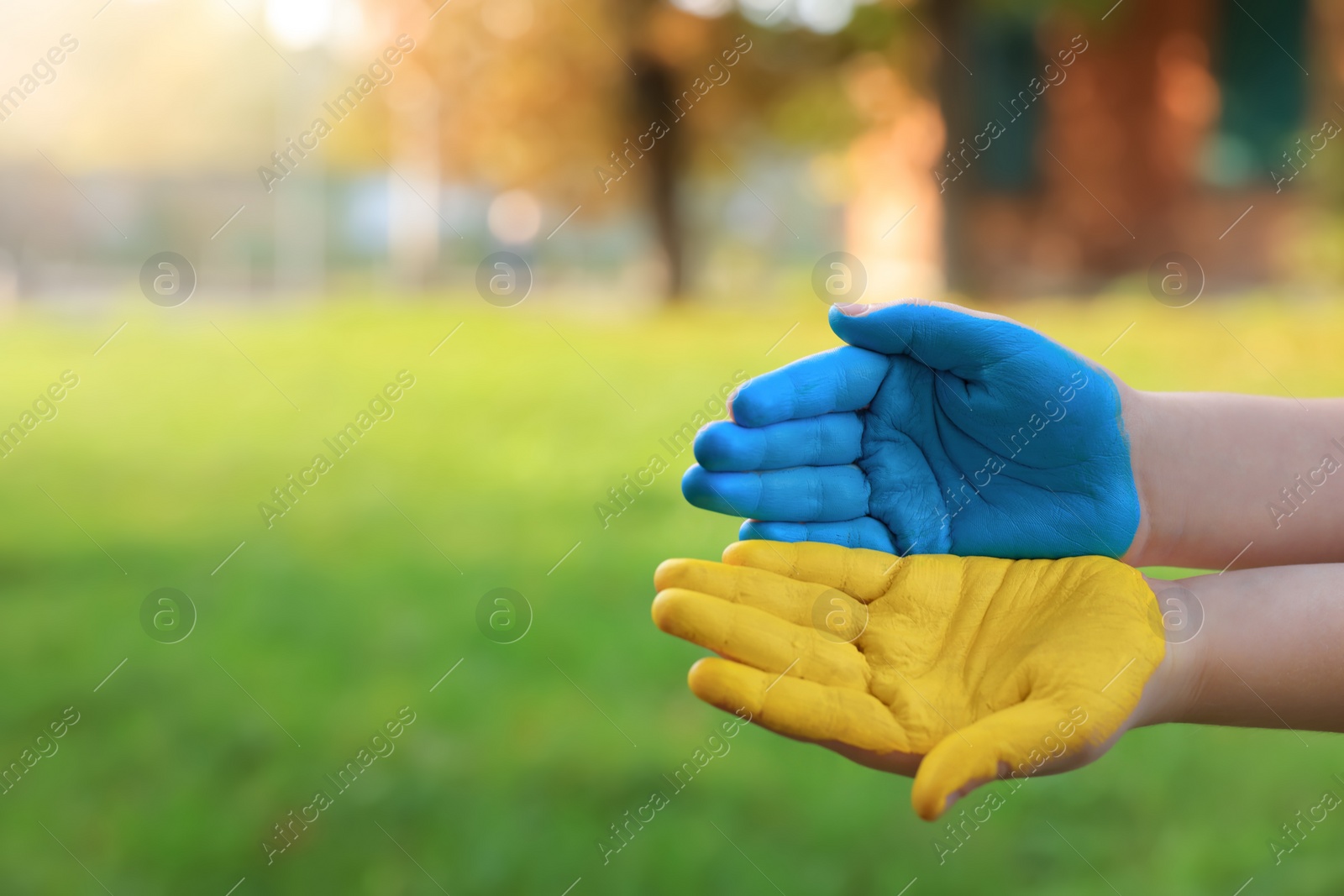 Photo of Little boy with hands painted in Ukrainian flag colors outdoors, closeup and space for text. Love Ukraine concept