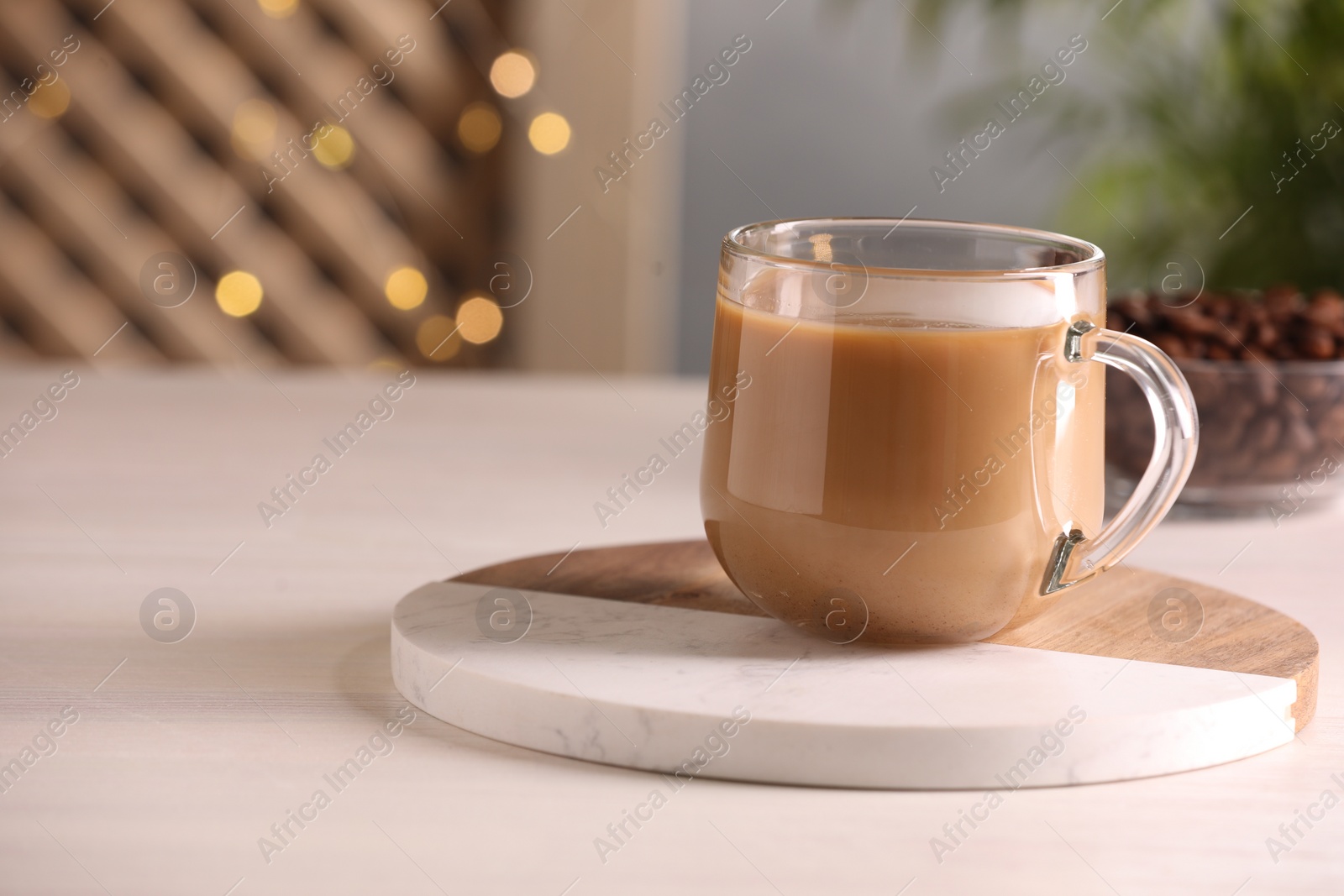 Photo of Delicious coffee with milk in cup on white wooden table, closeup. Space for text