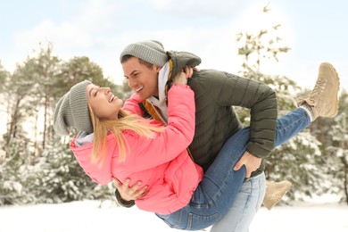 Beautiful happy couple in snowy forest on winter day