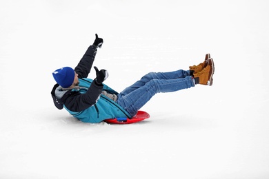 Man sliding on sled outdoors. Winter vacation