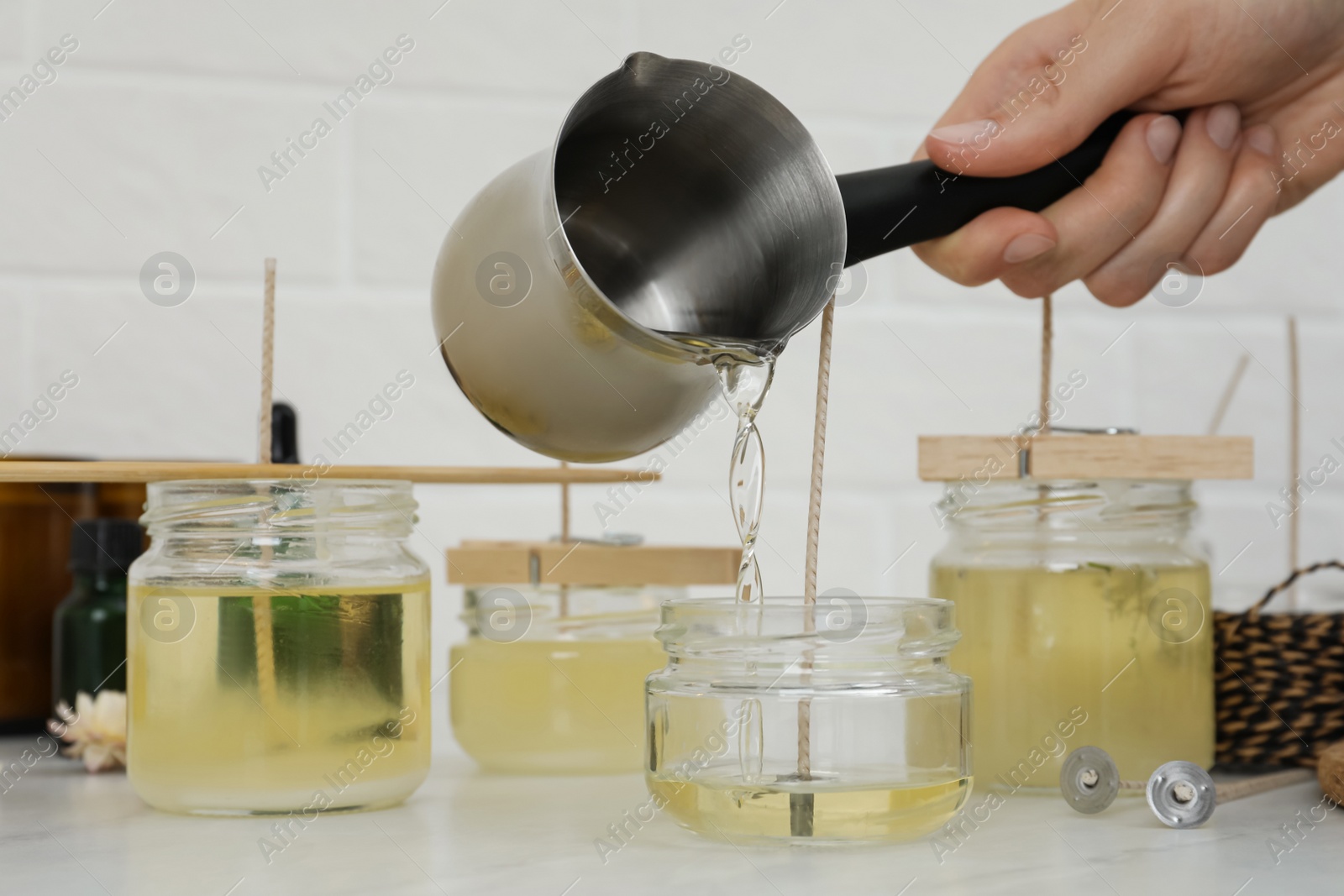 Photo of Woman making candles at white table, closeup