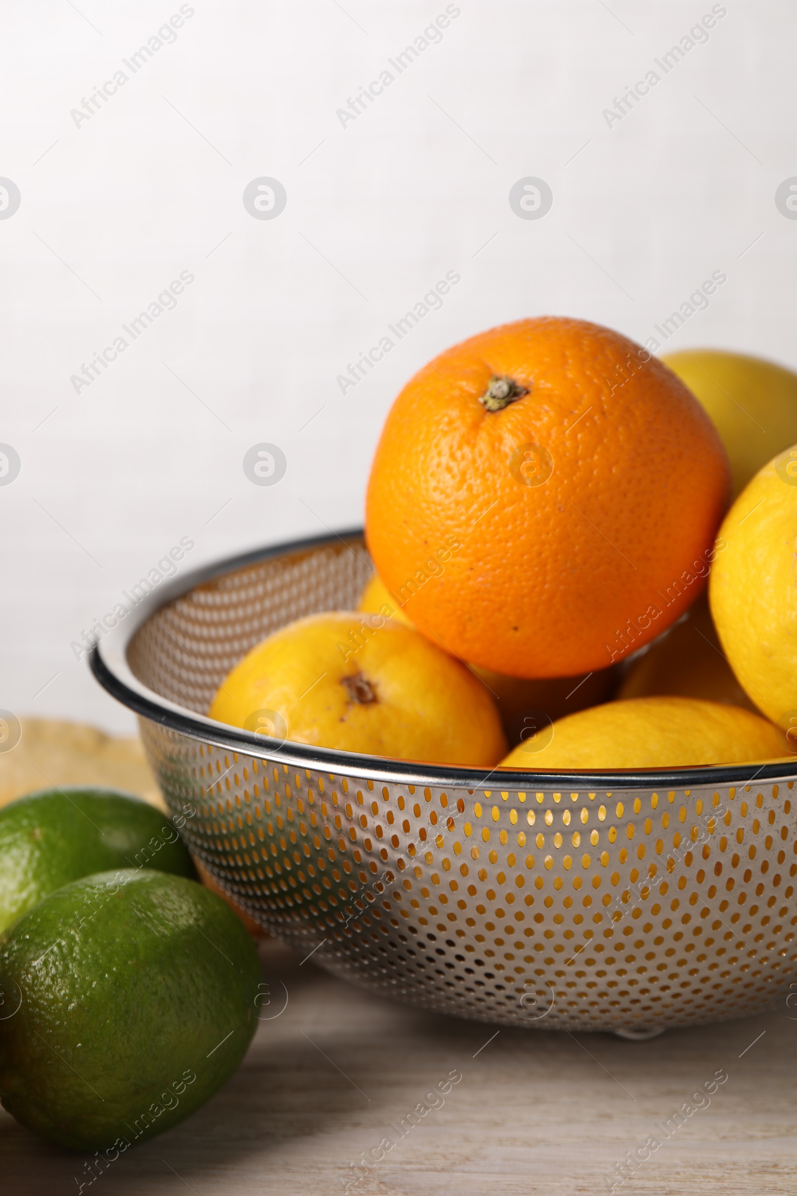 Photo of Different fresh fruits in colander on white wooden table, closeup