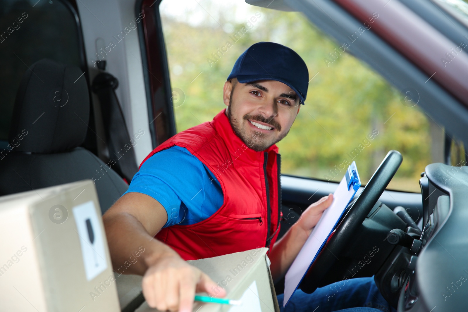 Photo of Young courier checking amount of parcels in delivery van